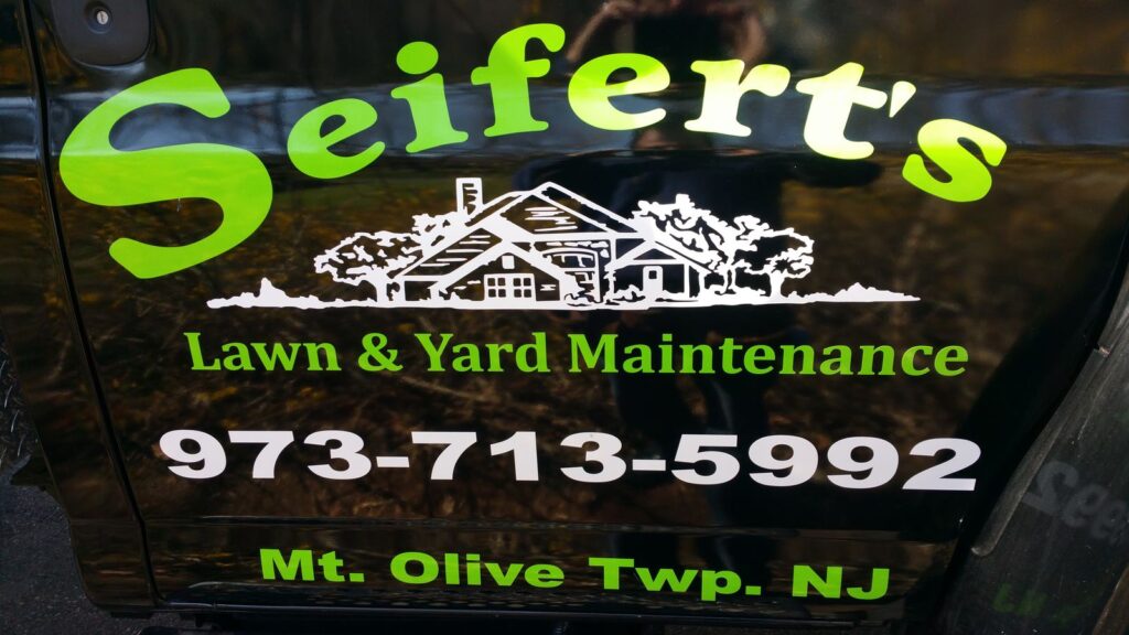 Seifert's Lawn & Yard Maintenance company name and phone number door lettering on a black work truck, Budd Lake NJ